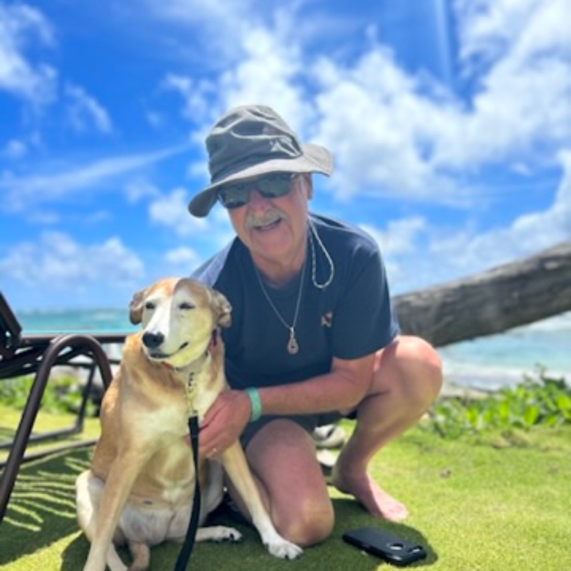 A man and his dog relaxing on a Hawaiian beach